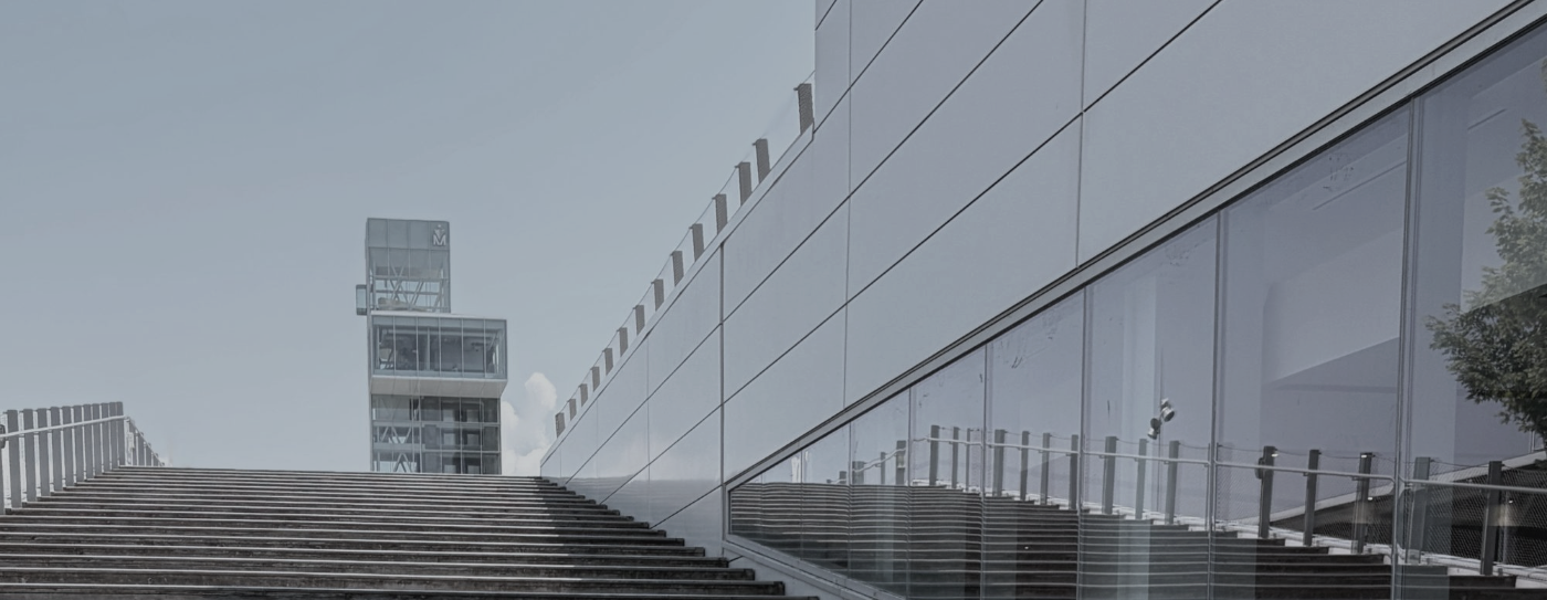 Stairs rising beside a glass and steel building toward an open sky